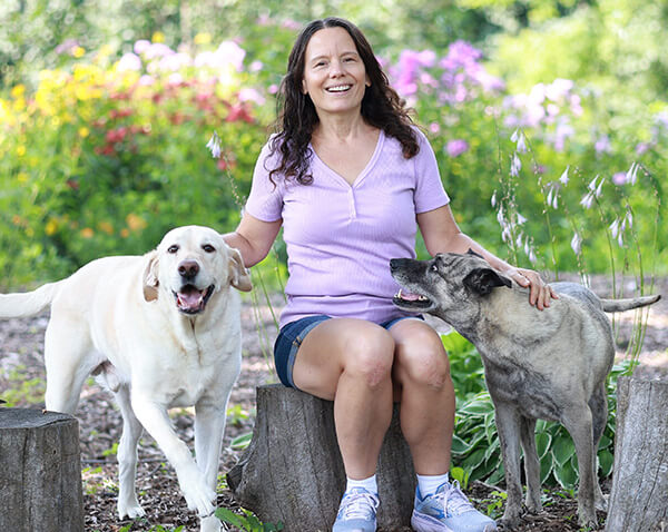 Debi McKee sitting outside with her dogs Ginger and Bear.